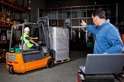 Man Working on Laptop in Warehouse